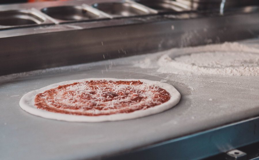 An image of a worker preparing pizza.