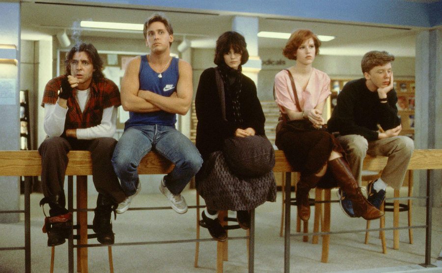 The cast of The Breakfast Club sit in the library. 