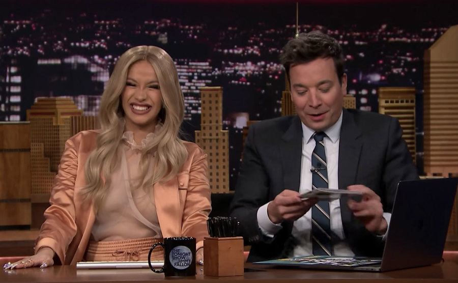 Cardi B sits beside Jimmy Fallon on set.