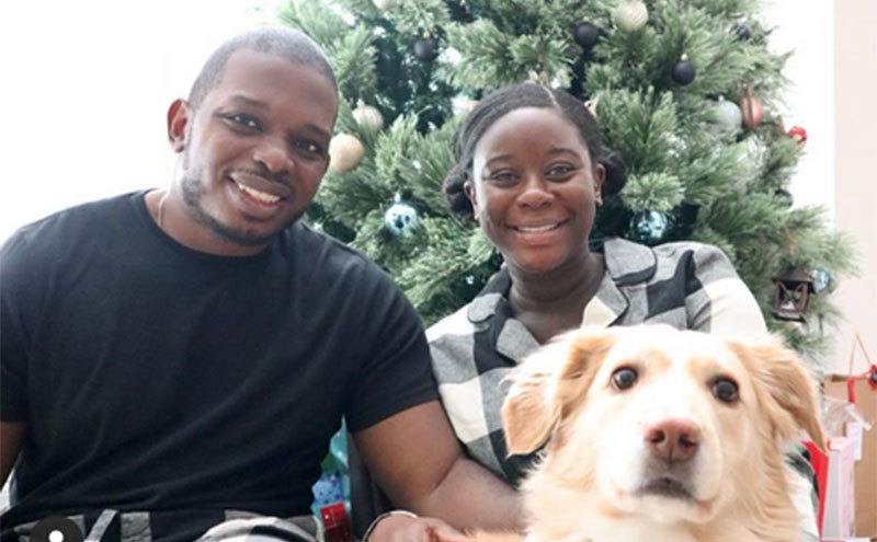 Deonna McNeill and Gregory Okotie take a photo with their dog.