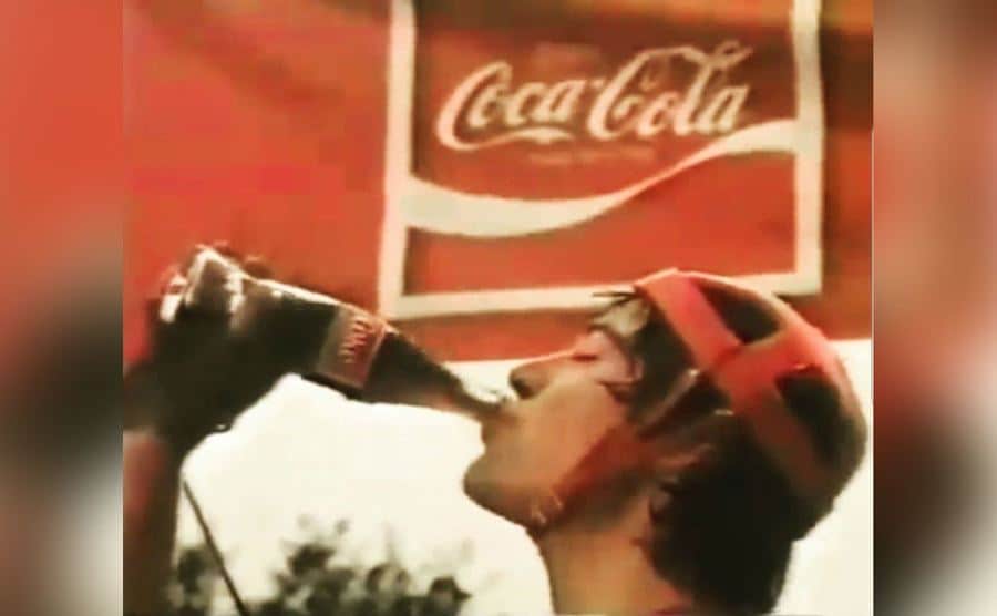 Keanu Reeves takes a satisfying sip from a Coca-Cola bottle.