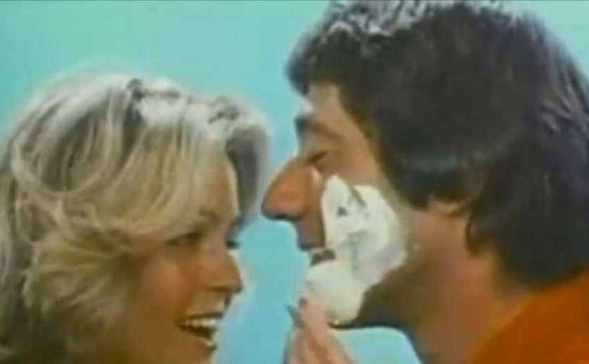 Farrah Fawcett applies shaving cream on a man’s face.