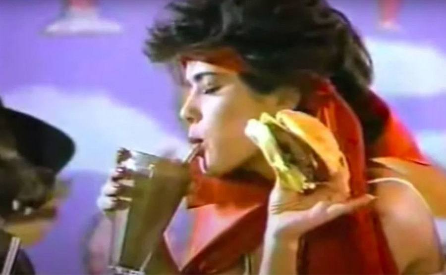 Salma Hayek is eating a burger and drinking a milkshake.