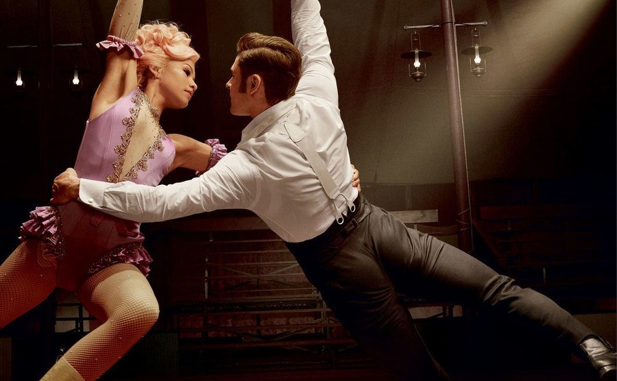 Zac Efron and Zendaya are swinging through the air on a trapeze.