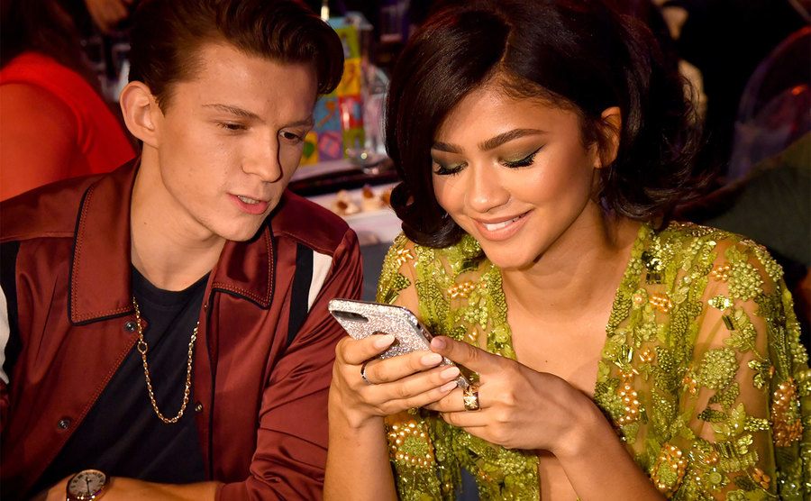 Tom Holland and Zendaya sit together at an event.