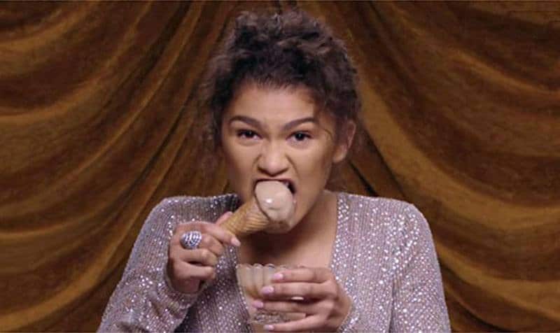 Zendaya takes a bite out of an ice cream cone during an interview.
