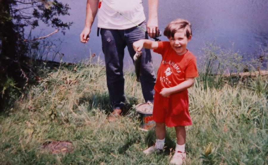 A dated picture of Michael fishing by a lake.