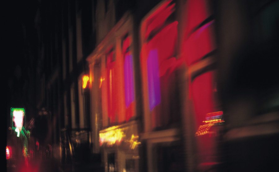 An exterior shot of the red lights at a strip club at night.