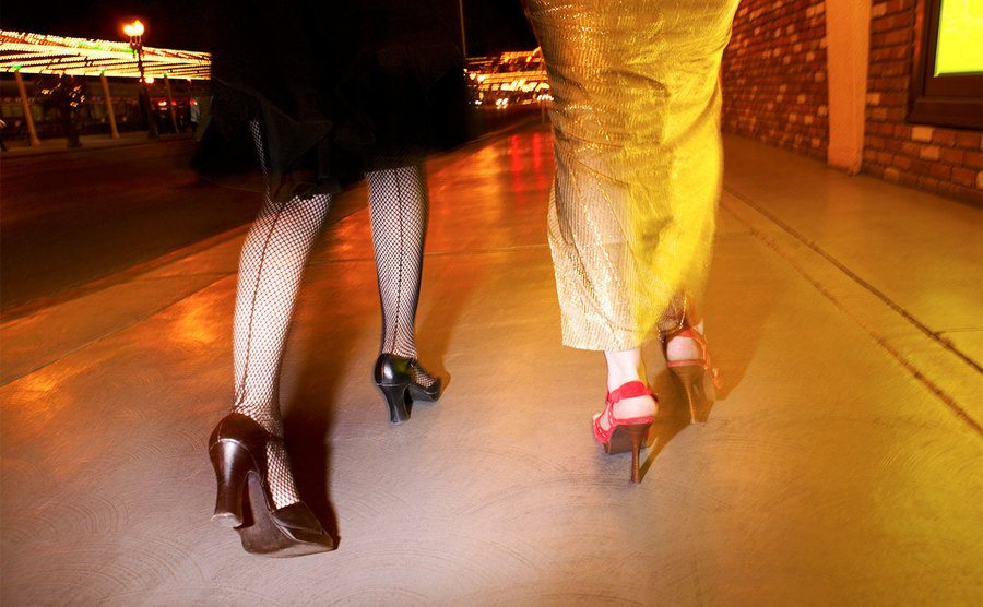 A closeup of womens’ legs walking at night.