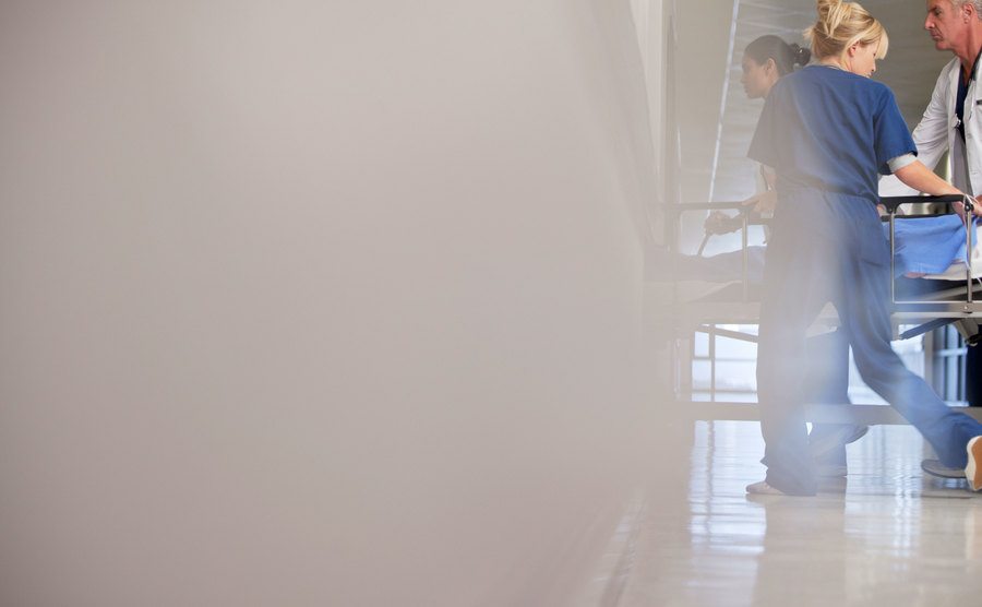 A photo of nurses and doctors wheeling a patient in a hospital corridor.