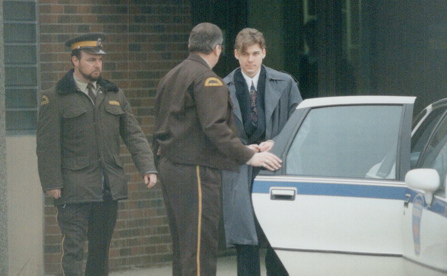 A picture of Paul Bernardo entering a police car.