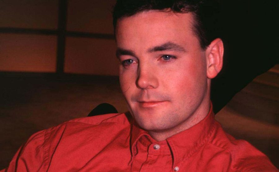 A photo of John during a televised interview.