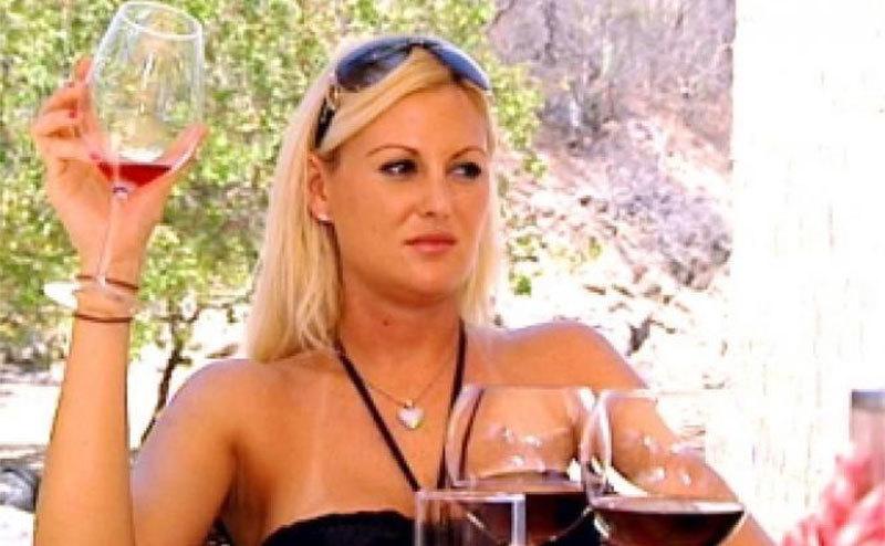 A still of Megan having a glass of wine in a still from the show.