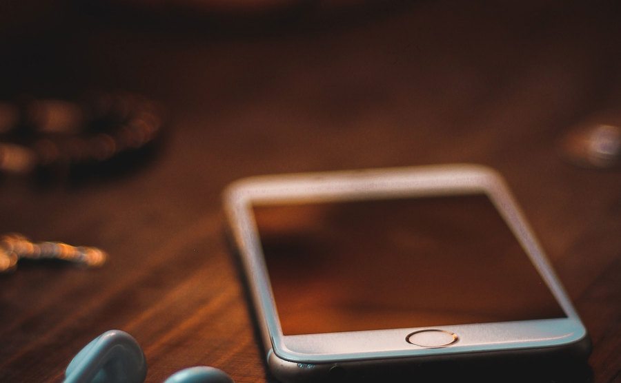 An image of a cellphone on top of a wooden desk.