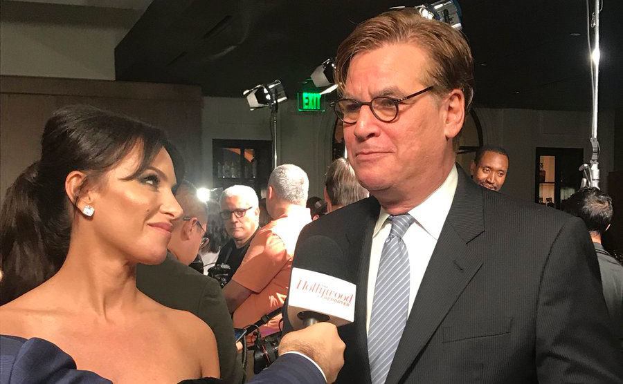 Sorkin answers questions for a reporter while standing beside Molly Bloom.