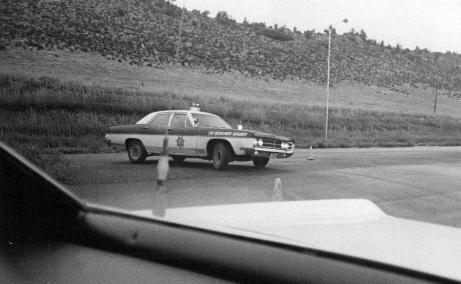 A photo of a police car stopping a vehicle on the highway.