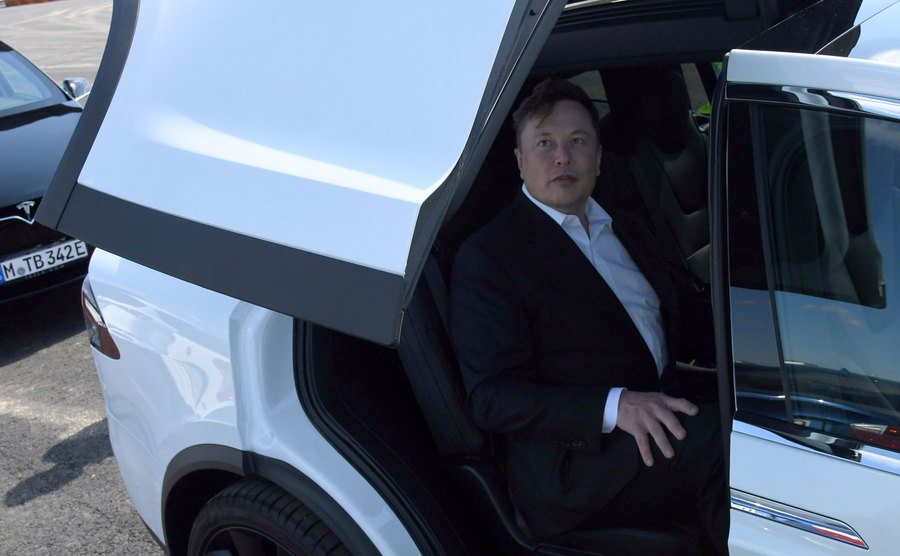 A picture of Elon Musk sitting in a Tesla.