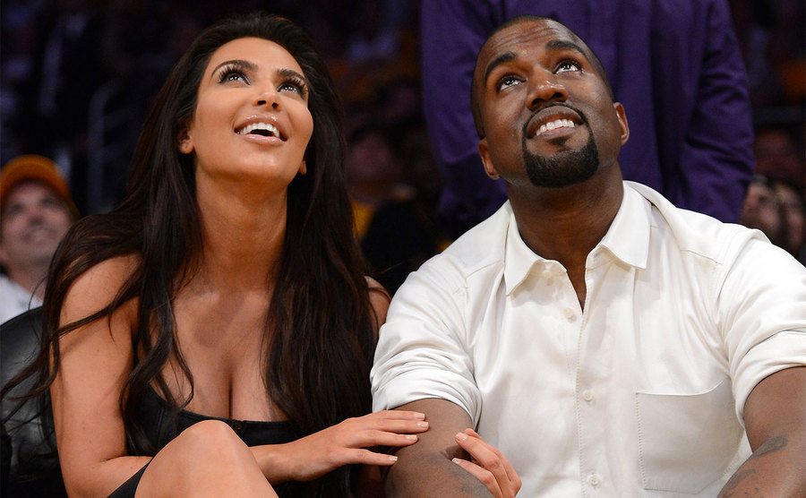 Kim Kardashian and Kanye West watch the video board from their courtside seats.