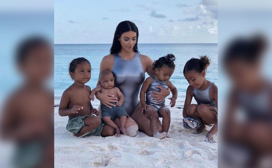 Kim poses for a photo on the beach with her kids.