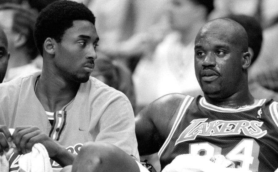 Kobe Bryant listens to O'Neal as they sit on the bench.
