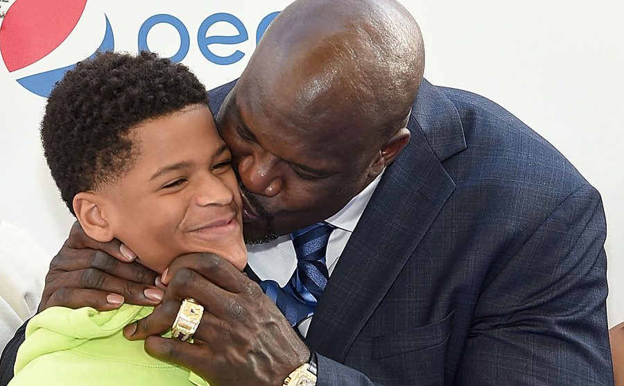 O’Neal kisses one of his sons as they pose for the press.