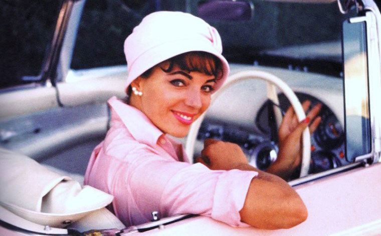 Joan poses for a photo as she sits in the driver’s seat of her pink car.
