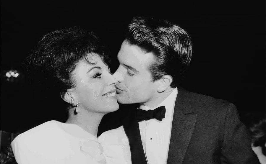 Warren Beatty kisses Joan Collins on the cheek as they attend a party.