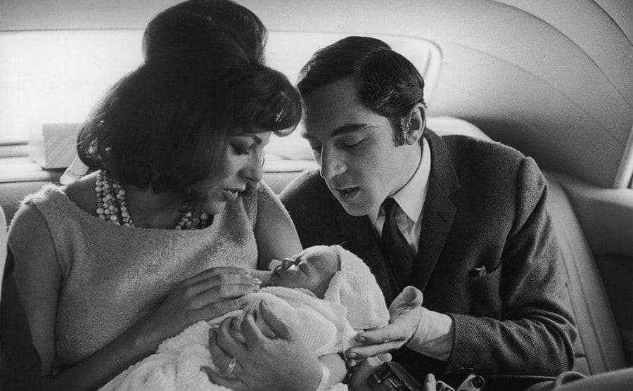 Joan Collins and Anthony Newley cradle their daughter Tara on the car ride home.