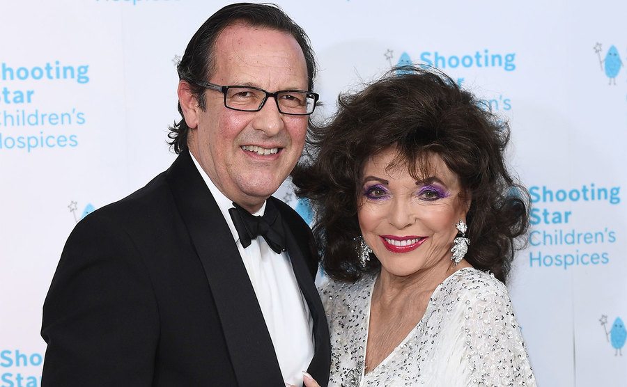Percy Gibson and Dame Joan Collins attend an event.