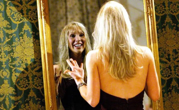 Beth views herself in a mirror after her transformation.