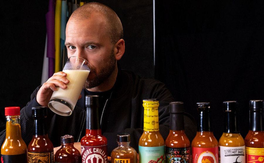 Sean Evans drinks a glass of milk as he looks over hot sauces. 
