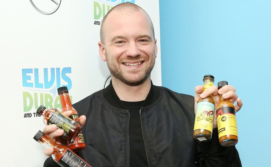 Evans poses with hot sauce bottles. 