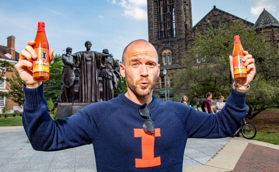 Evans holds up two bottles of hot sauce. 