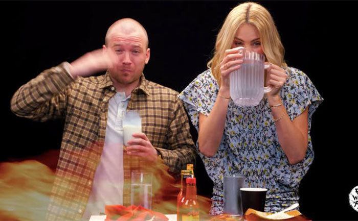 Sean Evans and Charlize Theron gulp down liquids to help with the spiciness. 