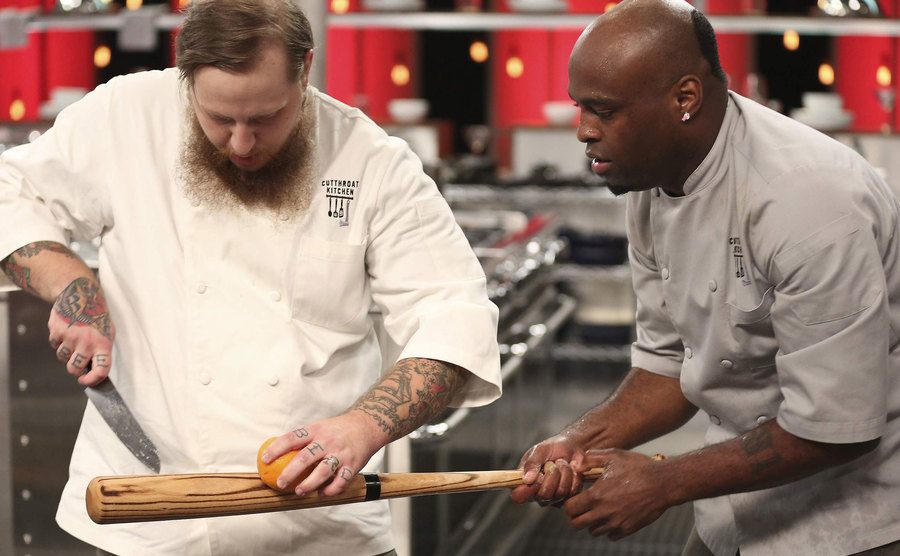 Competitors cut an orange over a baseball bat.