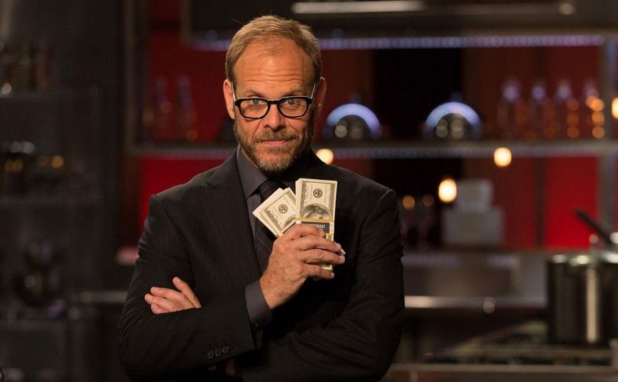 Alton Brown is holding the winning money.