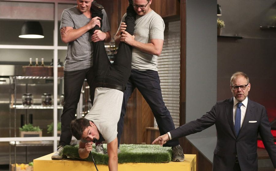 A competitor is held upside down while performing a challenge. 