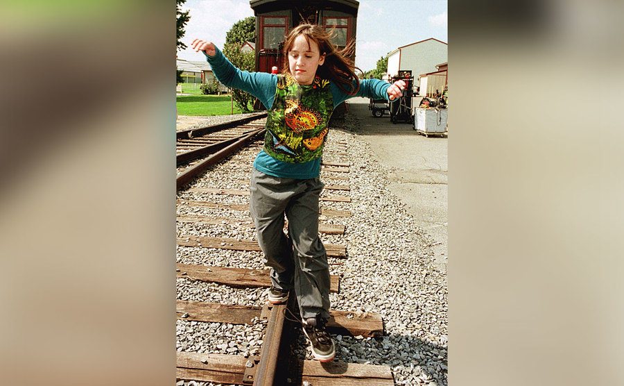 Mara Wilson, as Lily Stone, walks on the train tracks in a still from the film.