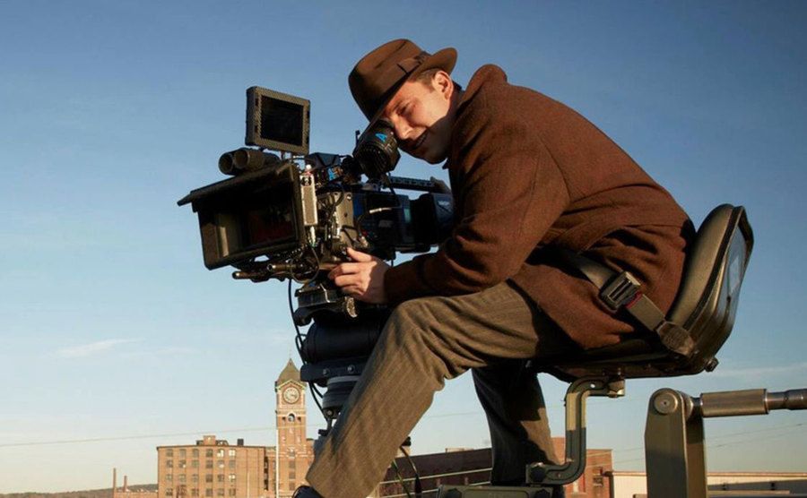 Ben Affleck sits on a crane while he films a scene. 