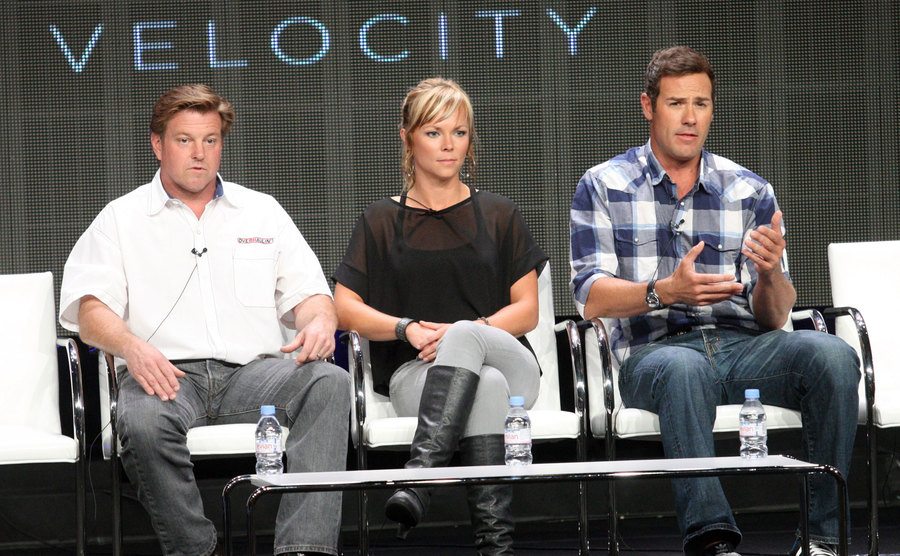 Chip and co-hosts Jessi Combs and Chris Jacobs speak on stage during a conference.