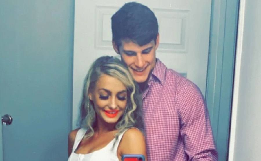 Moriah and Max take a picture standing in front of a mirror.