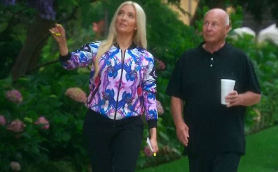 A still of Erika and Girardi walking in their garden.