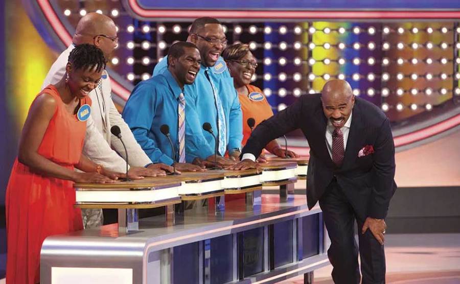 Steve Harvey is hunched over laughing on the set of Family Feud.