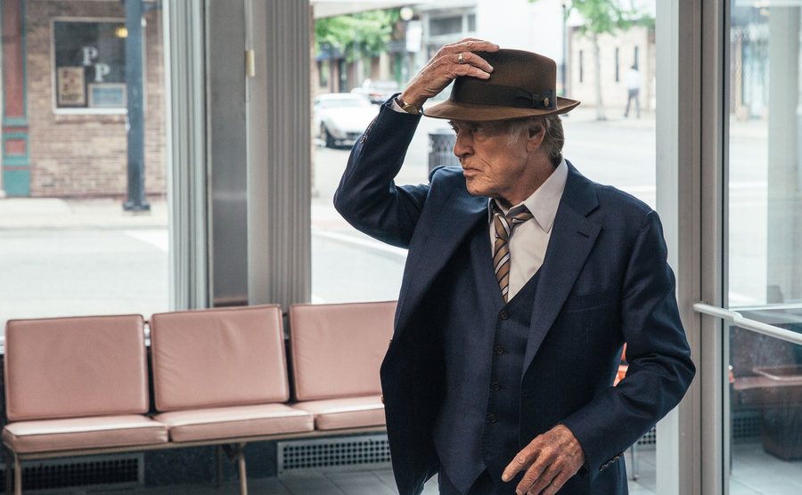 A movie still of Robert Redford walking, holding his hat.