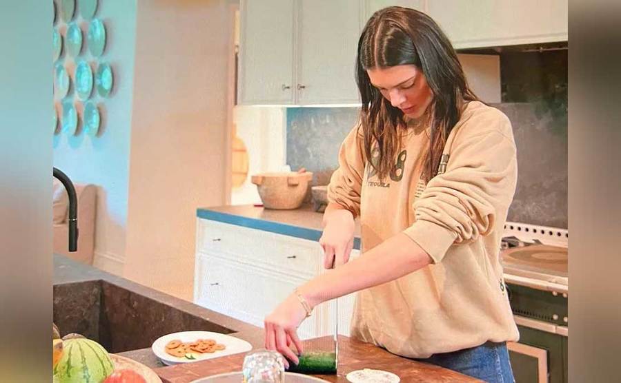 Kendall is cutting a cucumber in a very silly way.
