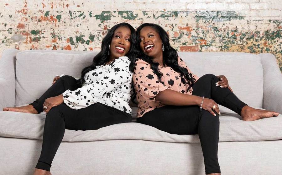 Patrix and Patrica pose back to back on the couch.