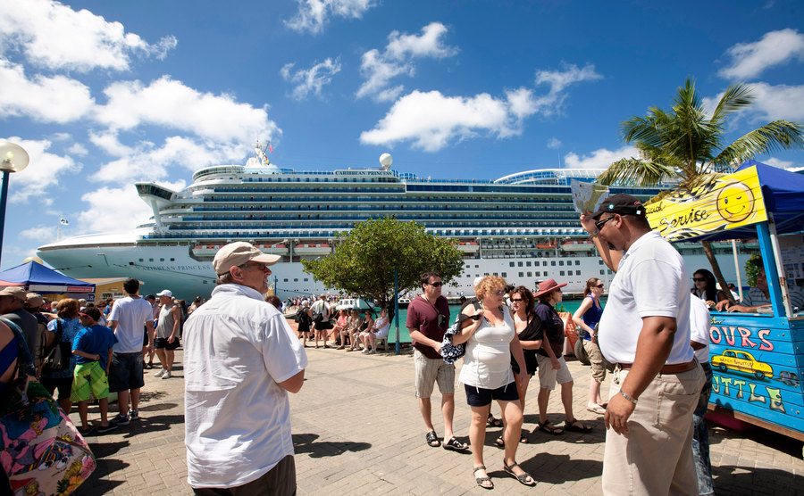 Passengers of a cruise ship walk in a harbour.