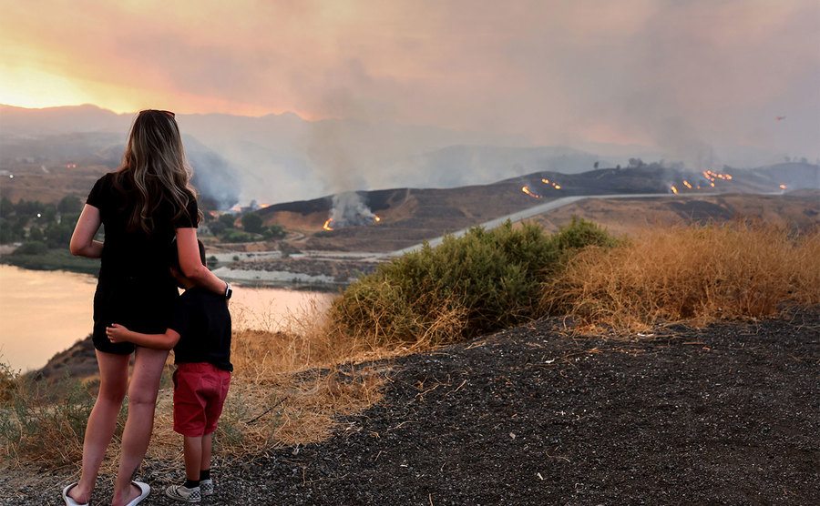 A woman and a child look over the remains of the fire. 