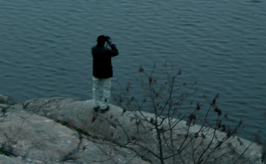 A man is searching for his dog by the waterfront. 