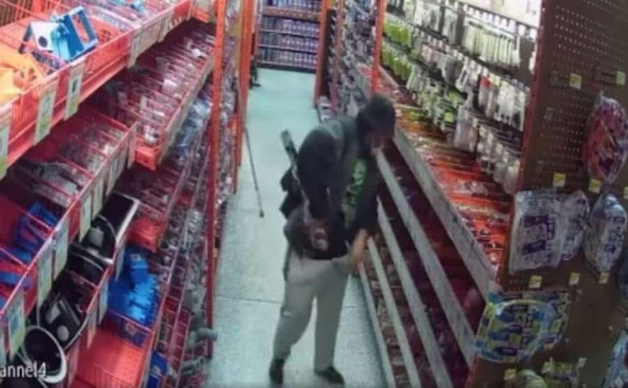 A man is stuffing a crossbow into his pants.